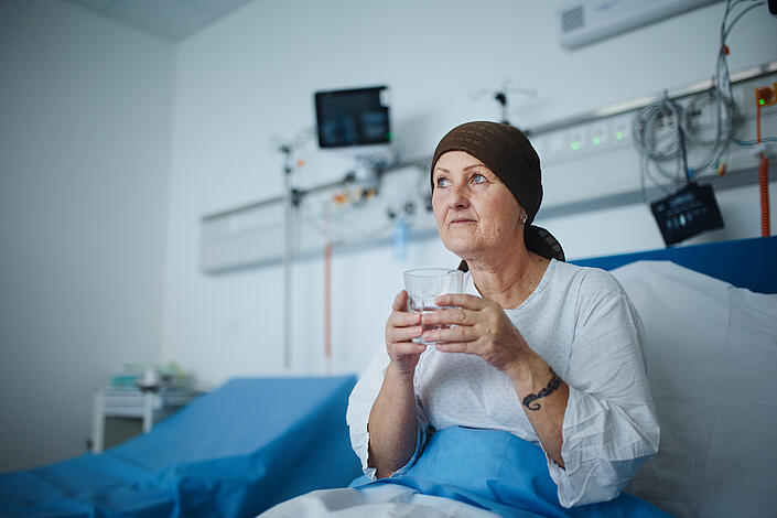 Eine Frau sitzt nach einer Chemotherapie im Krankenhausbett